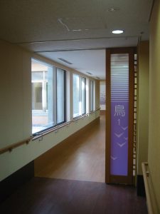 廊下から見た共用スペース。大きな窓から自然光が入る明るい空間